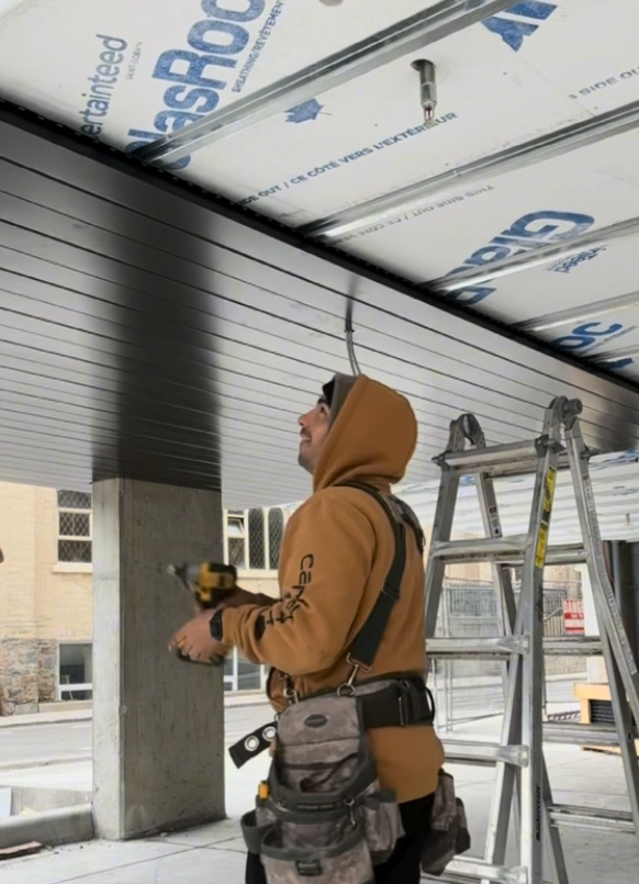Dark Metal Soffit Installation — Technician Fastening Panels — Primus Sheet Metal Corp. GTA